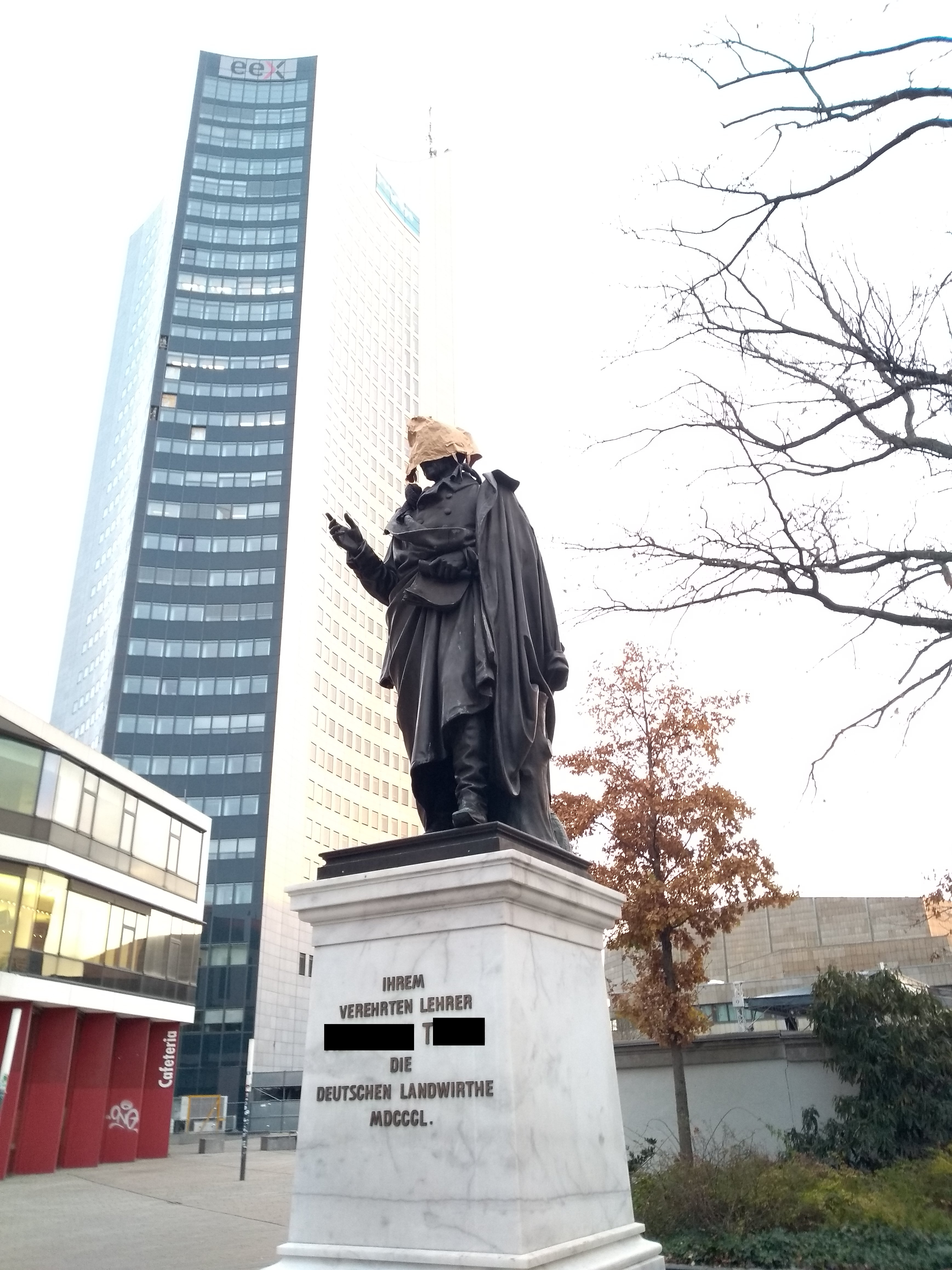 Statua von Thaler mit Papier-Einkaufstüte über dem Kopf